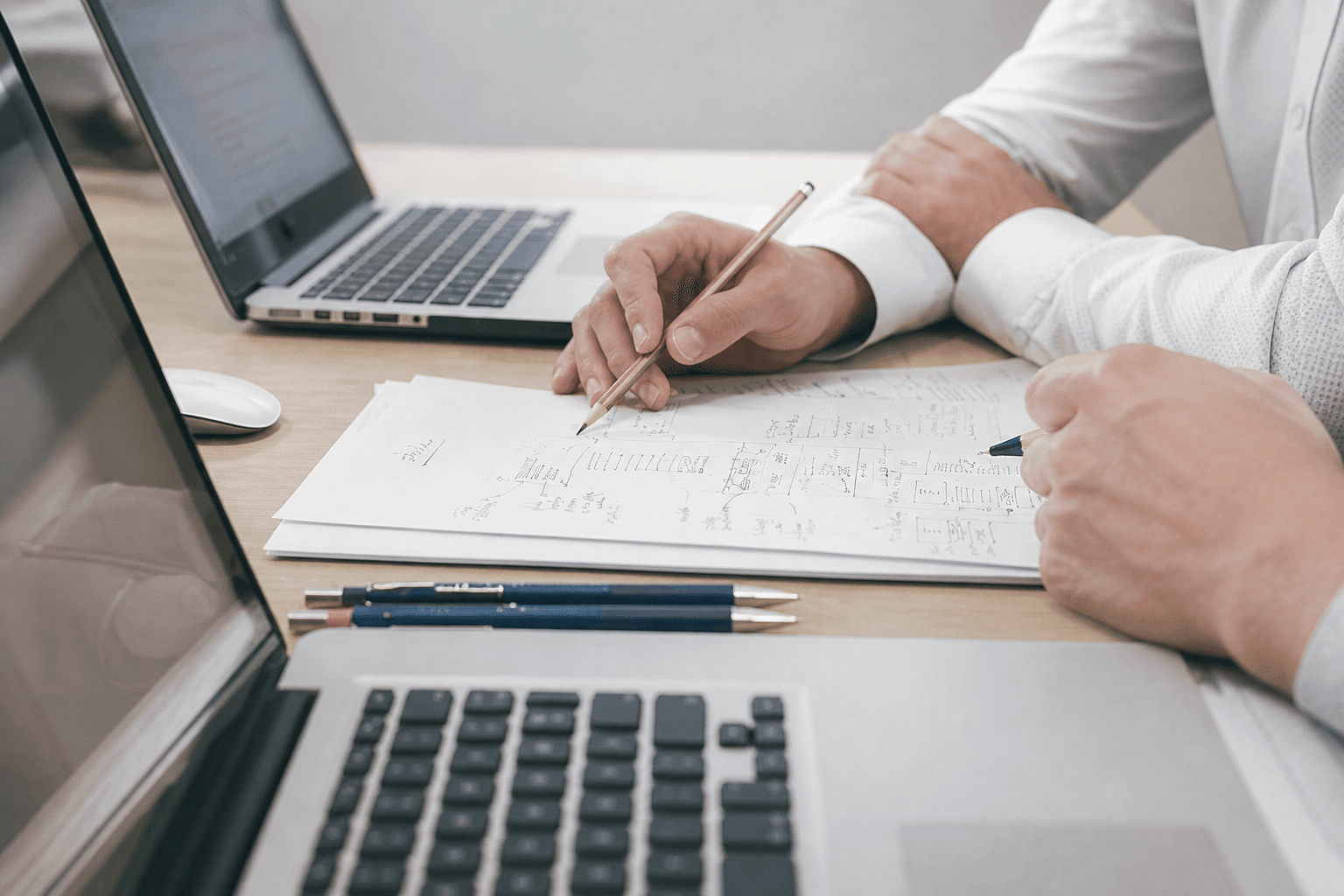 Two people collaborating at a desk with laptops and handwritten notes during a commercial finance consultation